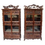 A fine near pair of Chinese hardwood wardrobes the flared cornices above frames ornately relief