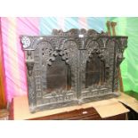 An ethnic, ebonised wall Cupboard having carved upper apron, on carved figure corbel supports,