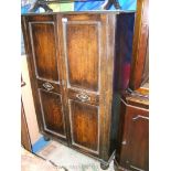 A 1920's Oak Hall Cupboard having opposing pair of two panel doors with applied,
