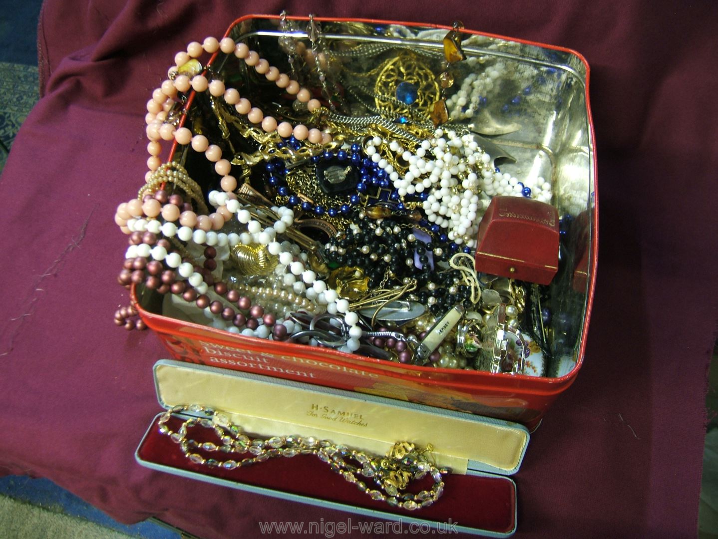 A tin of miscellaneous costume jewellery, beads, etc.