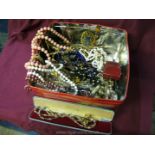 A tin of miscellaneous costume jewellery, beads, etc.