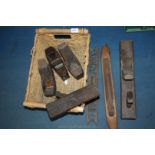 A basket of vintage wood tools including planes, levels,