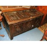 An antique Oak Coffer, having four carved panels to the lid, with repair,