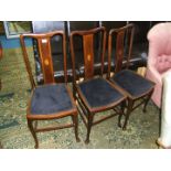 A set of three Edwardian Mahogany Dining Chairs having inlaid splats and black seats,
