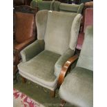 A pair of green draylon upholstered wing back Fireside Armchairs, standing on square Oak legs.