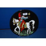 A pottery Wall Plate depicting a veiled rider on horseback in vivid colours,