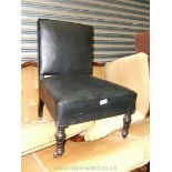 A low ebonised frame Nursing Chair in black leather effect upholstery.