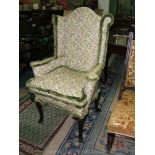 An antique mahogany and upholstered wing back armchair with finely carved hoof feet.