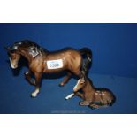 A Beswick jogging Mare and a foal lying down with one white sock and white blaze.