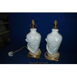 A pair of white Table Lamps with brass scrolled base, the lamp decorated with lilies,