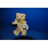 A small straw filled, jointed Teddy Bear with sewn nose and paw markings, glass eyes,