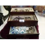 A large wooden jewellery box containing a mixture of necklaces, earrings,
