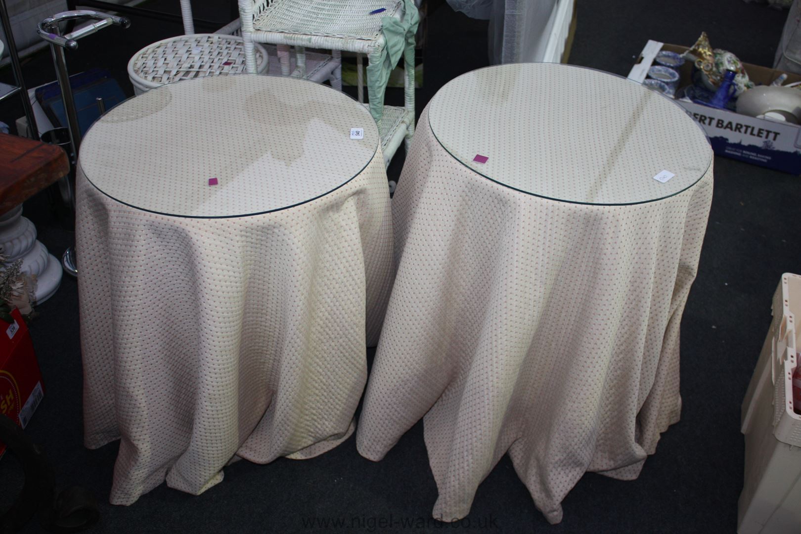 A pair of circular chipboard Bedside Tables with beige/red cloths and glass tops