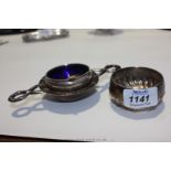 A Silver Mustard Pot with blue liner and a Silver Tea Strainer and stand