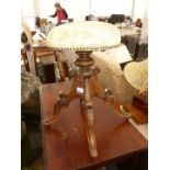 A Victorian revolving dark wood Piano Stool on four splayed feet.