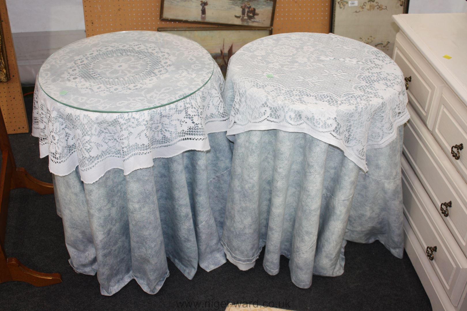 A pair of circular chipboard bedside tables with blue drapes