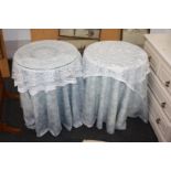 A pair of circular chipboard bedside tables with blue drapes