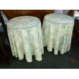 A pair of circular chipboard bedside tables with white and turquoise cloths and lace drape