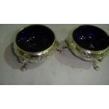 Early 19th century silver table salts with floral repousse work decoration with blue glass liners