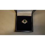 18 ct white gold ring set with a cluster of diamonds around a single emerald in presentation box