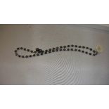 String of alternate strung black and cream coloured pearls as a necklace with flower shape mother