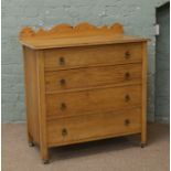 An oak four high bedroom chest of drawers with pine splashback.