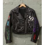 A ladies black leather biker jacket bearing motorcycle logos including Ace Cafe London, Triumph etc.