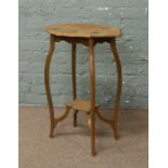 A walnut two tier window table with scalloped edge raised on slender supports.