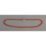 A red coral bead necklace with engraved 14ct gold lobed clasp.