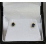 A pair of gold ear studs set with sapphires.