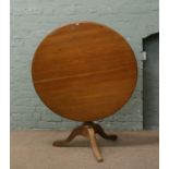 A mahogany tilt top table raised on tripod base.