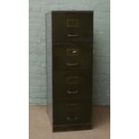 A vintage metal four drawer filing cabinet with brass handles.