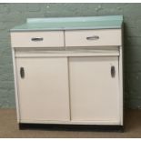 A 1950s painted kitchen cabinet with formica top and sliding doors.