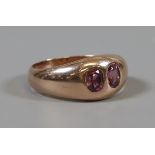 A 9ct rose gold ring set with a pair of rub over set almondine garnets, size N1/2.