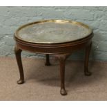 A mahogany circular coffee table raised on carved cabriole supports incorporating an Indian brass