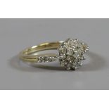 A 9 carat white gold diamond cluster ring with diamond set shoulders 0.25ct. Size K.