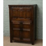 An oak cocktail cabinet with carved linen fold doors.