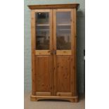 A modern pine two door wardrobe with partly glazed and panelled doors raised on bracket style feet