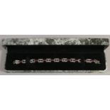 A cased Art Deco style silver bracelet set with red and white stones.