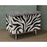 A painted childs toy box with zebra upholstered top and hydraulic hinge.