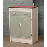 A 1950s kitchen utility cupboard with formica top and sage doors.