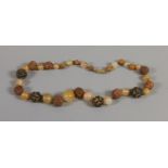 An orange carnelian and carved peach pit necklace.