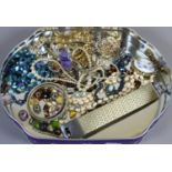 A tin of costume jewellery including simulated pearls and paste set brooches etc.