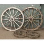 Four vintage wooden cart wheels with metal rims.
