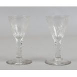 A pair of C19th cordial glasses with cut and engraved conical bowls raised on faceted stems.