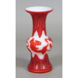 A Chinese Peking glass gu shaped vase with red overlay on a white ground with mythical beasts and