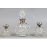 A large cut glass globular scent bottle and stopper with silver collar and two similar small