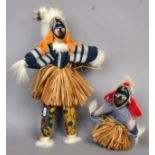 Two Ivory Coast dolls. Each wearing a dance mask and grass skirt.