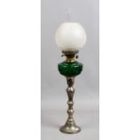An oil lamp with silver plated base and green glass font.