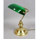 A brass based desk lamp with adjustable green glass shade.
